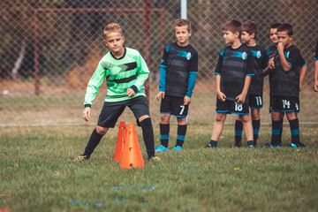 Fototapeta premium Boy in soccer jersey running between cones.