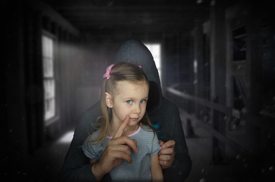 The criminal holds a frightened child and threatens him with reprisal. Children abuse is a crime don't be quiet about it.Criminal stealing baby in human child traficking concept.