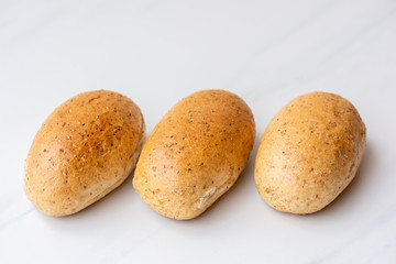Fototapeta na wymiar Tasty dark graham buns on white background, copy space. Bakery products, whole wheat buns