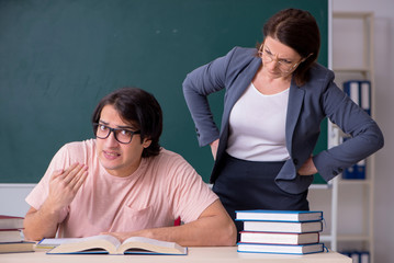 Old female teacher and male student in the classroom