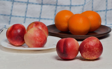 Fresh fruits in a plate, nectarine, orange, white background.delicious spanish orange on a wooden table, one cut in half.