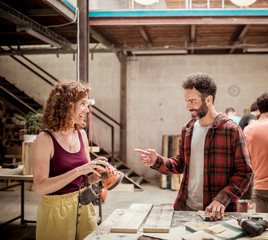 Smiling carpenters talking while working at workbench in workshop