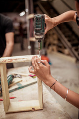 High angle view of female carpenter drilling wooden frame at workbench
