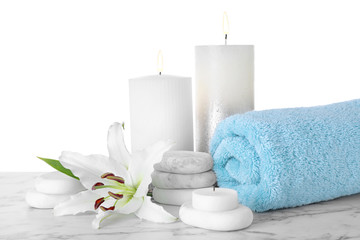 Composition with towel, spa stones and candles on marble table against white background