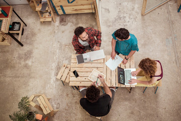 High angle view of colleagues discussing at desk while planning in workshop