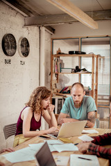 Female carpenter working with male colleague discussing over laptop in office at workshop