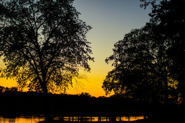 Vibrant orange sunset at boat landing on Wisconsin River with silhouette  trees  