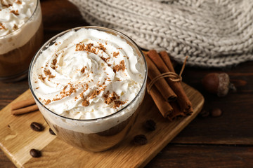 Glass with tasty pumpkin spice latte on wooden table