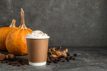 Paper cup with tasty pumpkin spice latte on grey table. Space for text