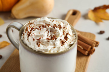 Cup with tasty pumpkin spice latte on light table, closeup