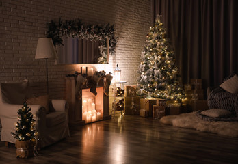 Fototapeta na wymiar Stylish interior with beautiful Christmas tree and artificial fireplace at night
