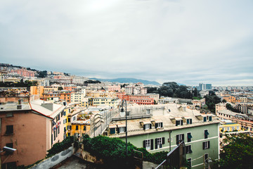 Fototapeta na wymiar Many beautiful old italian houses painted in bright colors with mountains on the background.An amazing cityscape of some public housing in Genova built in the 60s over hills of the city in cloudy day,