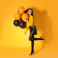 Beautiful woman with balloons on yellow background. Halloween party