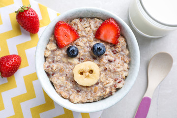 Tasty porridge served with berries and milk on marble table, flat lay. Creative idea for kids breakfast