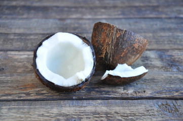 Half a coconut lies on a wooden table. White pulp and coconut shell