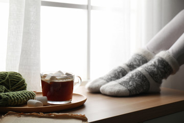 Woman and cup of hot winter drink near window indoors, closeup