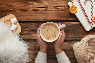 Woman with cup of coffee at wooden table, top view. Cozy winter