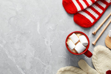 Flat lay composition with cup of tasty cocoa on grey marble table, space for text. Cozy winter