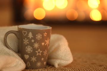 Obraz na płótnie Canvas Cup of hot drink on wicker mat against blurred background. Winter atmosphere