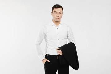 Obraz na płótnie Canvas Young businessman wearing in a casual style outfit. The man is posing in a white long sleeve shirt with jeans and holding a jacket on his hand. Concept of men's fashion.