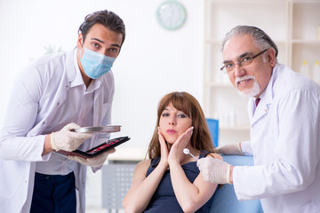 Two male doctors and young woman in plastic surgery concept