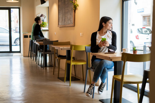 Smiling young woman in a cafe looking out of window