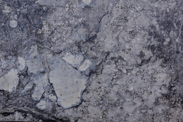 White and grey granite, limestone, or travertine surface with random black organic natural deep bumpy scratch pattern on surface.