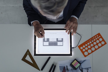 Senior businessman drawing on shining tablet