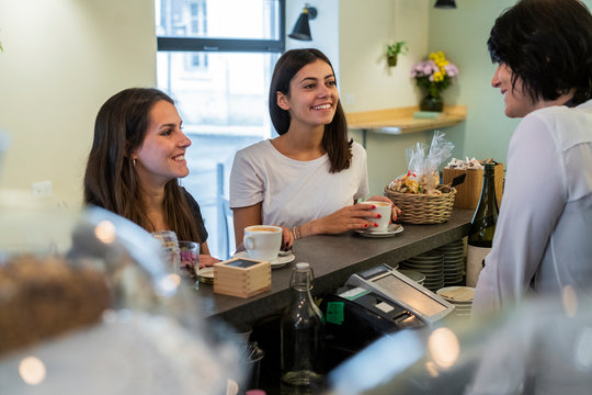 Two happy young female, friends at the counter in a cafe