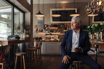 Senior businessman with cell phone in a cafe
