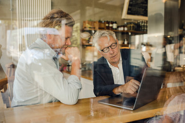 Two businessmen with laptop meeting in a cafe