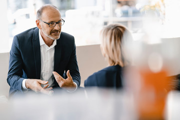 Businessman and woman having a meeting in a coffee shop, discussing work