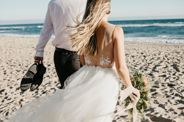 Rear view of bride and groom walking on the beach