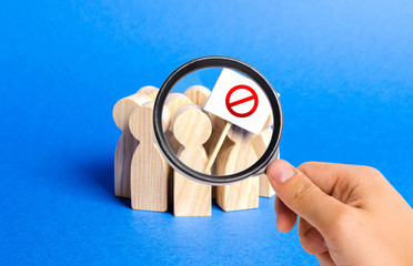 A magnifying glass looks at an angry mob of people with a poster. Social discontent and tension,...