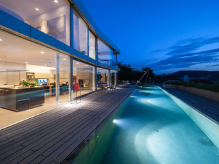 Switzerland, lighted modern villa at dusk with terrace and pool in the foreground