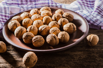 Whole walnuts on a plate.Whole walnuts on rustic old wooden table.Trace elements zinc, magnesium, healthy food.