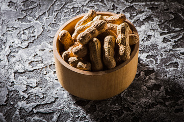 Dried peanuts or nuts on wooden background.Boiled peanuts (amendoim cozido, sergipe, nordeste, Brazil) in a black and yellow bowl and boiled peanuts spread and open outside the bowl.