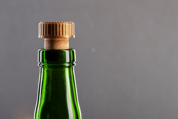 Green wine bottle with cork on dark background, close-up view