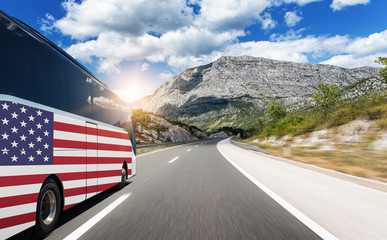 A bus with the flag of the United States of America rushes along the highway. Trip to usa - concept.