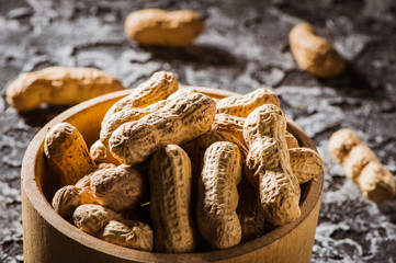 Peanuts in a wooden bowl on the table.Peanuts in shells on wood background.Mixed Nuts. Healthy food and snack. Top view.