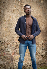 Hombre joven negro de Senegal, atlético, con abdominales marcados y la camisa desabrochada.