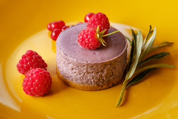Tasty dessert cheesecake with raspberries and currants on a yellow background. 