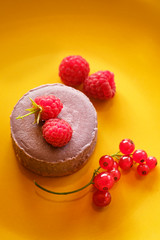 Tasty dessert cheesecake with raspberries and currants on a yellow background. Flat lay food