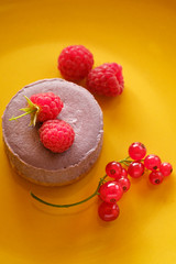 Tasty dessert cheesecake with raspberries and currants on a yellow background. Flat lay food
