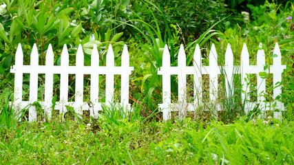 Low white fence on the green grass. Life in the cottage and in the country