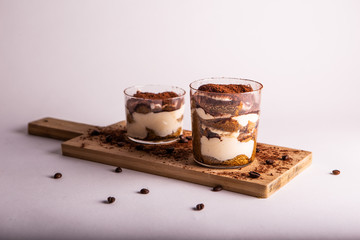 Italian tiramisu mono portion on wooden cutter board. White background, close up