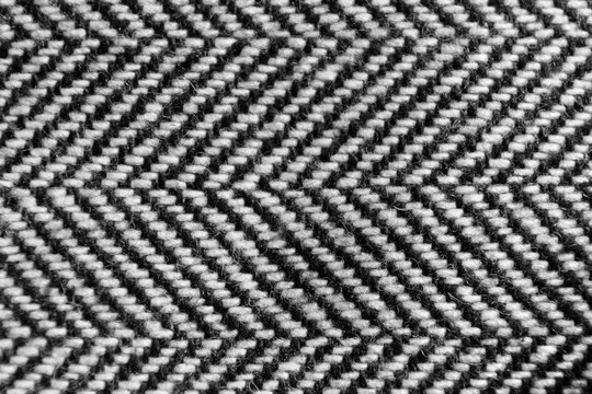 The herringbone tweed wool fabric texture background closeup. Natural organic wool cloth with classic pattern