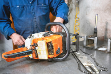 Mechanic repairing a chainsaw. Man repairing a chainsaw in workbench .