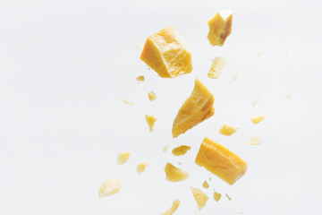 Fototapeta Parmesan cheese flying in different directions with crumbs on a white background with space for the text. obraz