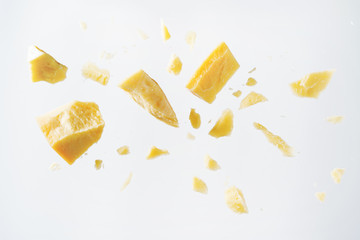 Parmesan cheese flying in different directions with crumbs on a white background with space for the text.